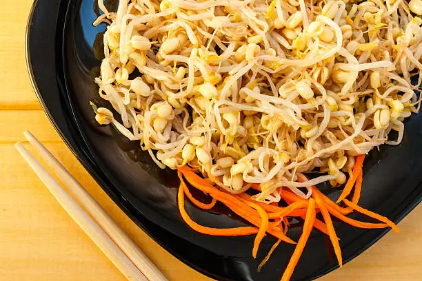 beansprouts salad on black plate on wooden desk, close-up