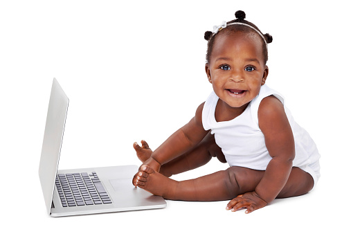 Studio shot of an adorable baby girl using a laptop isolated on white