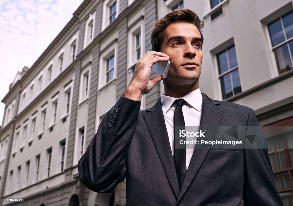 Networking with clients A handsome businessman in a suit talking on the phone in a city setting Adult Stock Photo