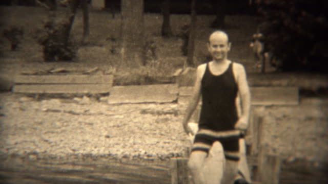 1938: Wealthy man walking on lake dock in hilarious 30s style swimwear.
