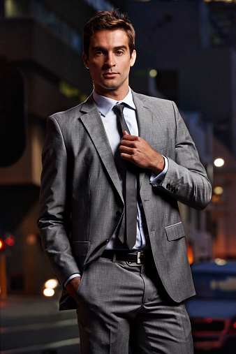 Portrait of a handsome businessman in a suit standing in a city setting at night