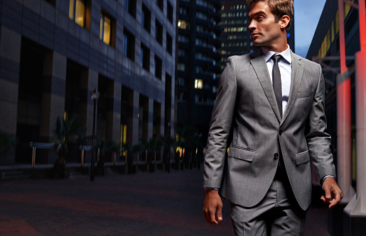 Shot of a handsome businessman in a suit walking through the city at night