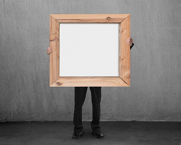 istock man hold blank whiteboard with wooden frame in concrete room 527876417