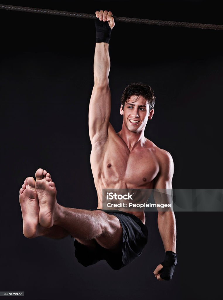 Maximum power! Studio shot of a young man doing pull-ups from a bar Chin-Ups Stock Photo