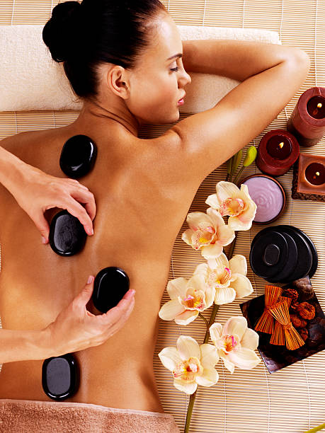 Adult woman having hot stone massage in spa salon Adult woman having hot stone massage in spa salon. Beauty treatment concept. hot stone massage stock pictures, royalty-free photos & images