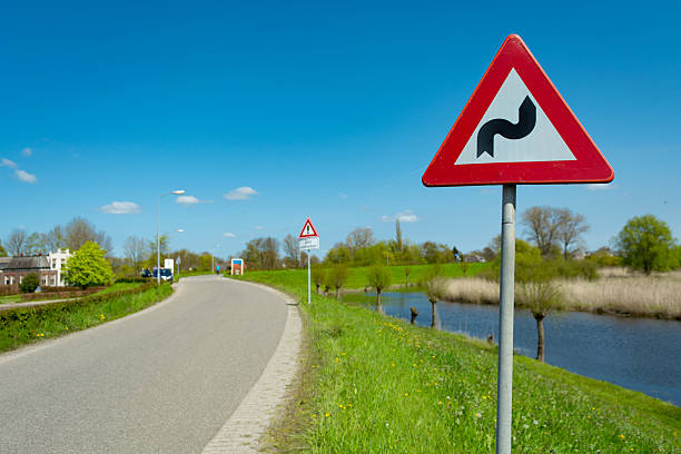 dangerous curves traffic sign on  road, focus on sign, sunny blue sky