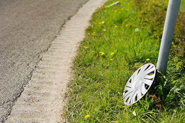 lost plastic hubcap on the edge of the road, standing against a pole on the grass on road bend