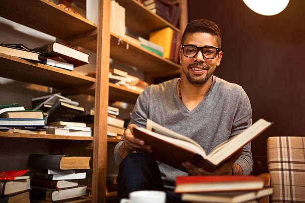 istock Smiling African American student reading a book in library. 527883662