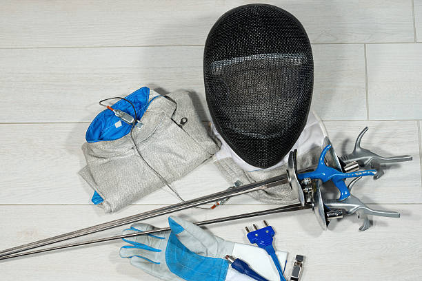 Fencing Foil Equipment Fencing foil equipment. Three fencing foils with pistol grip (sporting weapon), a fencing mask and a blue and white glove on floor pentathlon stock pictures, royalty-free photos & images