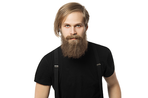 the attractive man the blonde with long hair of the European appearance with a beard in a black t-shirt and black trousers on a white background