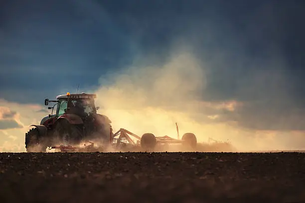 Photo of Farmer in tractor preparing land with seedbed cultivator