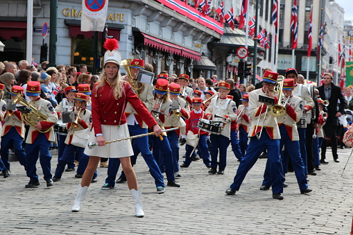 Oslo, Norway - May, 17, 2012: The national day parade making it's way down Karl Johan, the main street in Oslo, towards the castle. On the right hand side is Grand Hotel. The parade consists in elementary schools in oslo and their marching bands, Here is a school marching band which is dancing while they play, rather than marching.