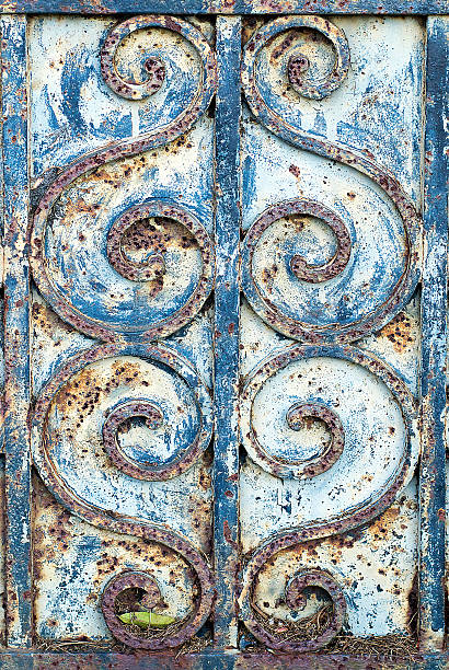 Closeup of iron swirl details on an old, rusty blue door.