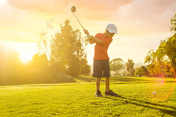 garoto golfista dar a primeira tacada durante o pôr-do-sol - child swing swinging balance - fotografias e filmes do acervo