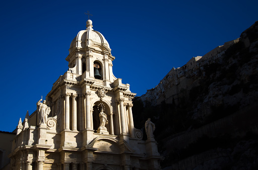 Scicli, Sicily: the baroque facade of the Church of San Bartolomeo in dramatic light. The church dates to the 15th century and was partially rebuilt in baroque style in the 18th century. Scicli is a UNESCO World Heritage site. Copy space available.