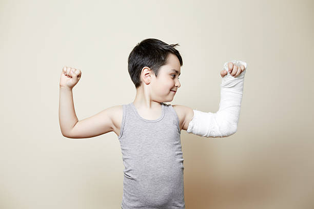 cute boy with broken arm nice smiling boy with hand in cast flexing biceps orthopedic cast stock pictures, royalty-free photos & images