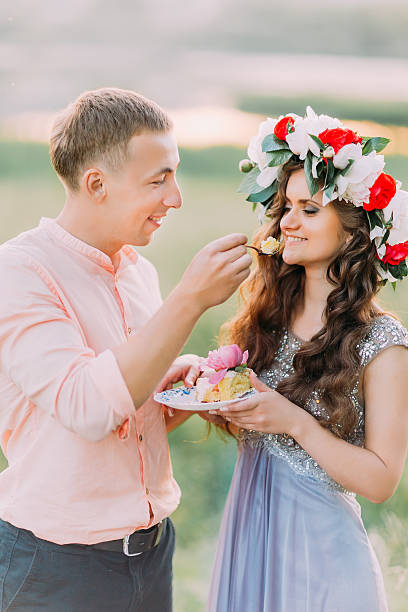 istock Handsome man in peach shirt feeding girlfriend with piece of 527896934