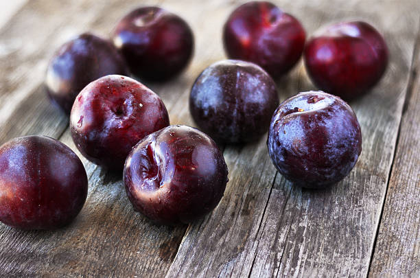 prunus domestica. maturi prugne su backgraund in legno. - prugna foto e immagini stock