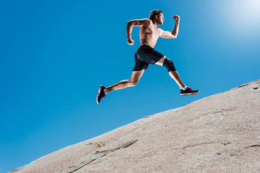 Male Running Up A Granite Boulder In The Mountains