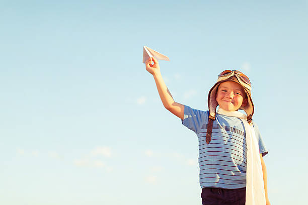 istock Young Boy Dressed as Pilot Flies Paper Airplane 527901174