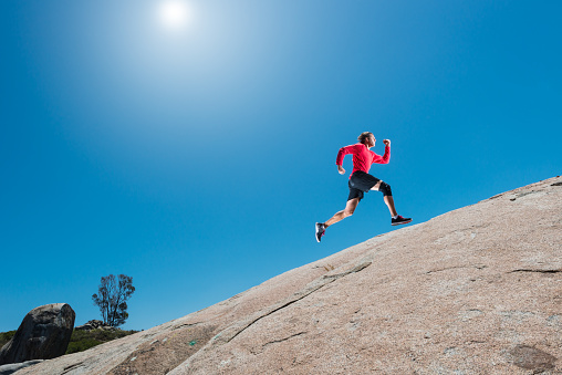 Male Running Up A Granite Boulder In The Mountains