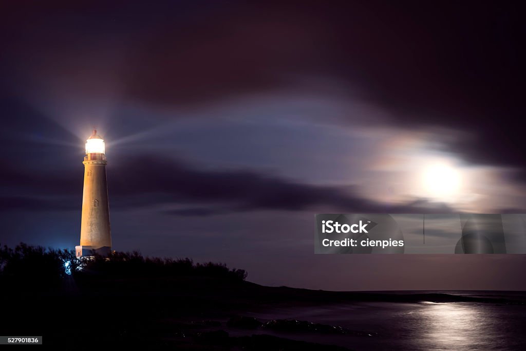 Lighthouse on beach coast at night with moon sky Lighthouse on coast at night with moonlight in the sky, beach environment landscape. Lighthouse Stock Photo