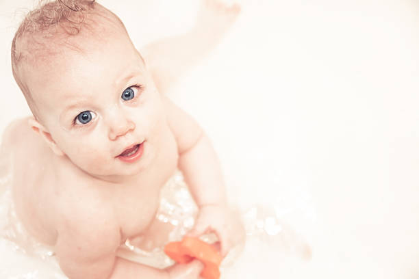 istock Cheerful baby looking up at camera while playing in bath 527901842