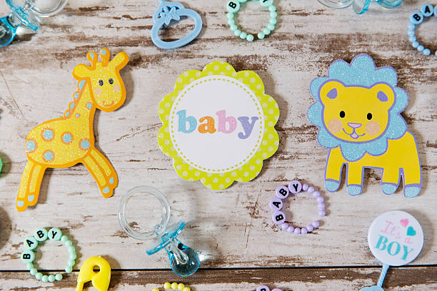 Baby shower theme Baby shower flat lay for a boy. Includes baby rattles, bracelets, safety pins, pacifier, a giraffe and lion baby bracelet stock pictures, royalty-free photos & images