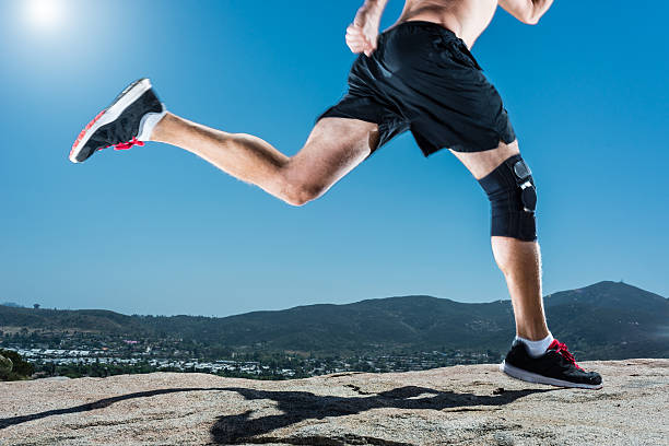 Knee Brace Running Up A Granite Boulder In The Mountains Male Running Up A Granite Boulder In The Mountains knee brace stock pictures, royalty-free photos & images