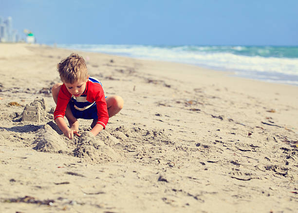 istock little boy play with sand on summer beach 527908208
