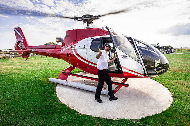 About to take a helicopter ride over Twelve Apostles Port Campbell, Australia - March 20, 2011: Helicopter pilot from "12 Apostles Helicopters" is inviting to take a seat in the helicopter before a tour over the Twelve Apostles at the Great Ocean Road twelve apostles sea rocks victoria australia stock pictures, royalty-free photos & images