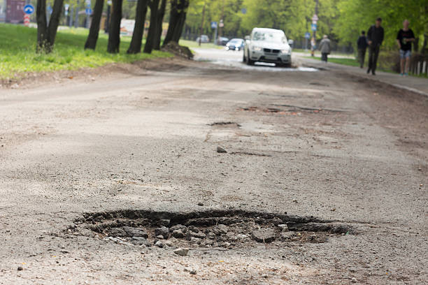 istock pothole on the road near the manhole 527910064