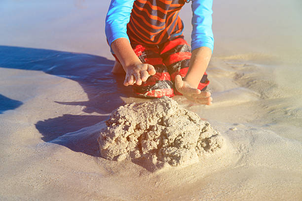 istock little boy play with sand on beach 527910490