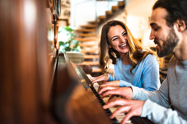 french couple playing the piano in a parisen house french couple playing the piano in a parisen house piano stock pictures, royalty-free photos & images