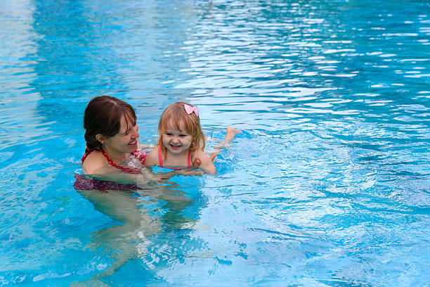istock mother teaching little daughter to swim 527911524