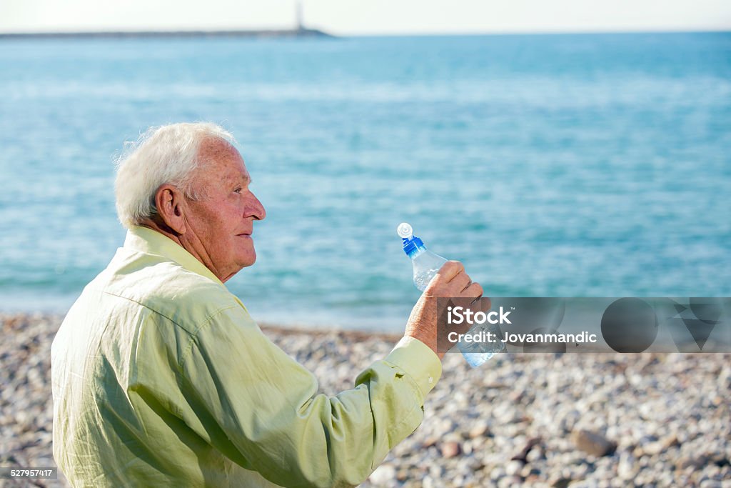 Senior Man On The Sea An elderly man drinks water from a bottle and watch the sea 70-79 Years Stock Photo