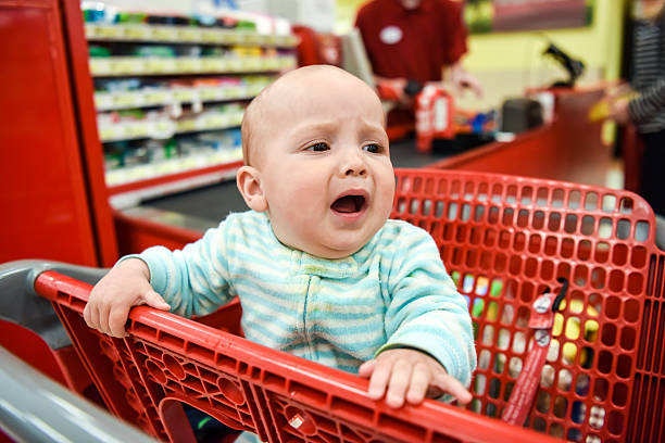 Crying Baby sitting in a shopping cart looking away
