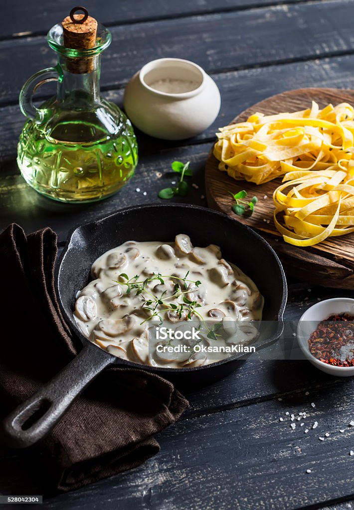 Ingredients for cooking pasta with creamy mushroom sauce Ingredients for cooking pasta with creamy mushroom sauce - dry pasta, mushroom cream sauce, olive oil and spices. On a dark wooden background. Healthy delicious food Cheese Stock Photo