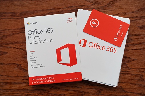 West Palm Beach, USA - January 2, 2016: Microsoft Windows Office 365 home subscription  software  package. Package includes Word, Excel, Powerpoint, OneNote, Outlook, and one terabyte cloud storage. Contents of package is partially pulled from box and the key code card is also visible. 