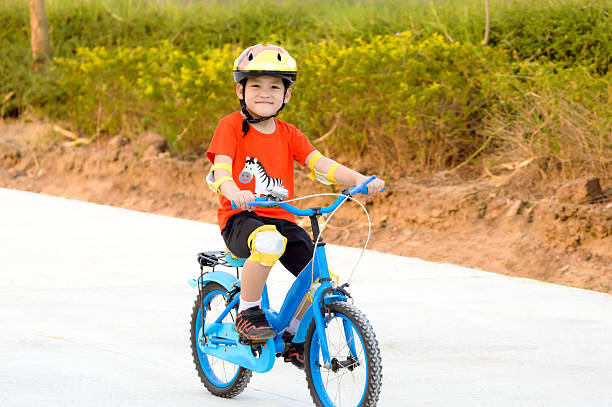 little girl rides a bike on a green meadow in nature.