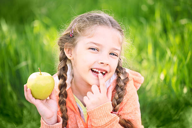słodka dziewczyna z się dostać toth posiadanie jabłko w - apple eating little girls green zdjęcia i obrazy z banku zdjęć