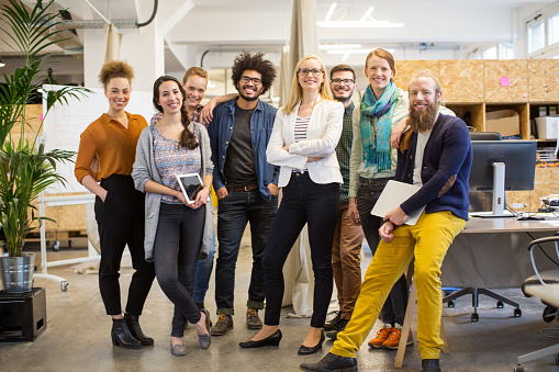 Portrait of multi-ethnic business people smiling together. Full length of happy colleagues are in smart casuals. Confident professionals are in creative office.