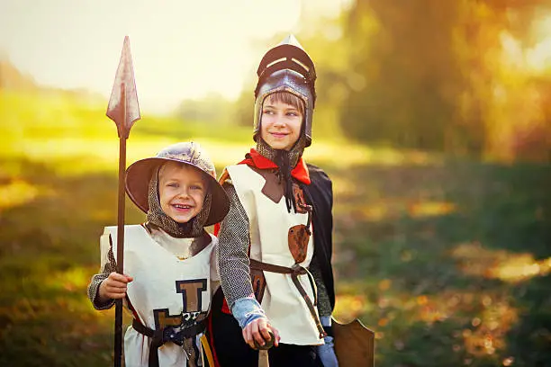 Kids dressed up as knight and squire playing in forest. Little boy is aged 6 and the girl is aged 9.