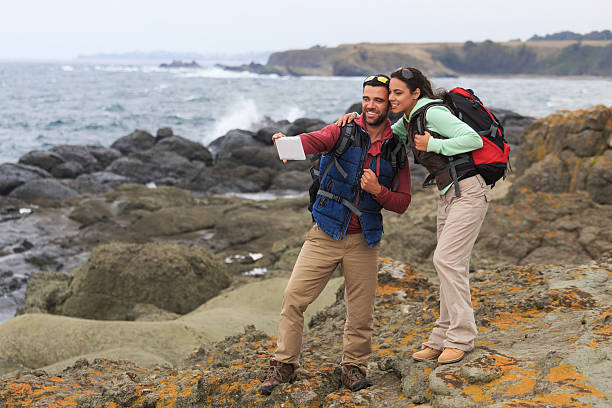 istock Cheerful couple standing on rocks and making selfie 528050952