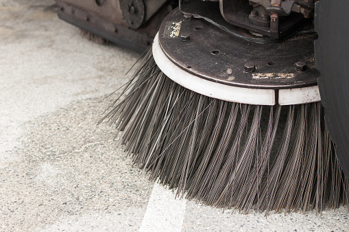 A close-up of a street sweepers brush. The cleaning equipment is mounted to a truck that is driven through the streets to sweep and vaccum up trash in the streets.