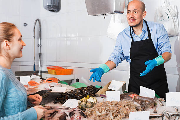 istock Mature seller helping female customer to choose  fish 528051874