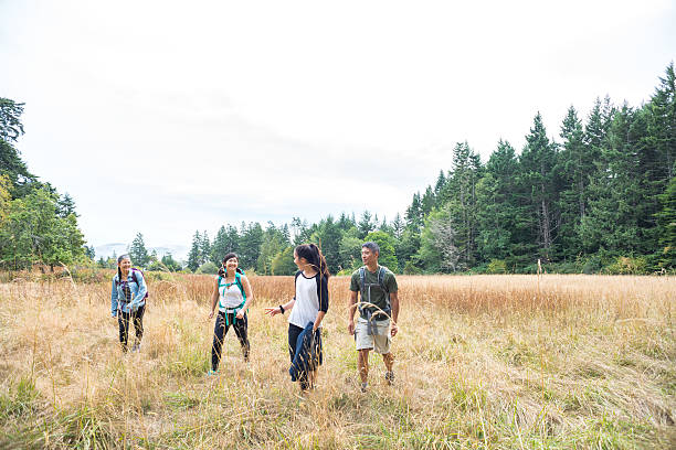 Happy Multi-Ethnic Family Hiking Through Grassy Meadow Surrounded by Forest