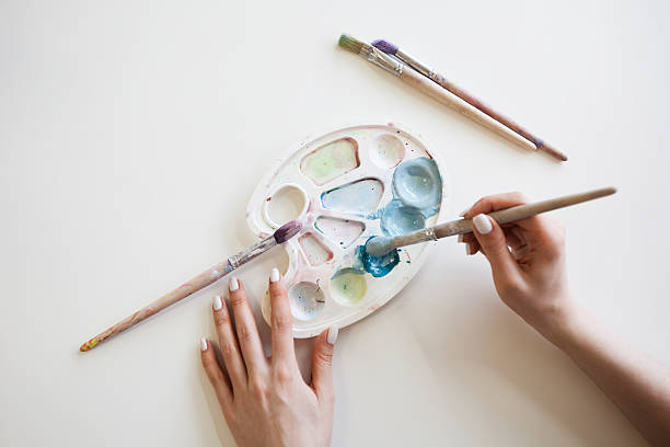 istock Female hands with colorful palette and brushes 528054872