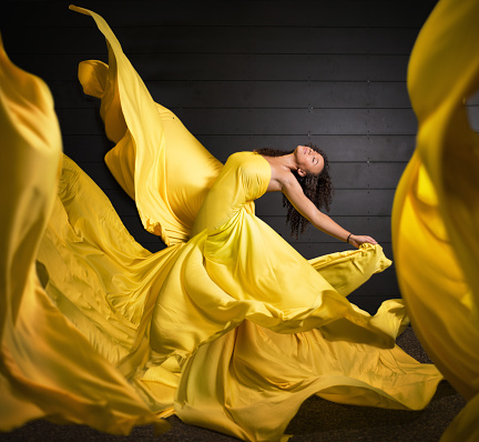 Shot of a a woman dancing surrounded by flowing yellow fabric