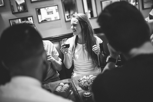 Multi ethnic group of friends toasting with red wine in a bar. They are happy with smile on their faces.